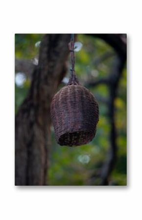 Close-up of a wicker lamp with a blurred garden background