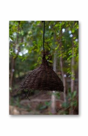 Close-up of a wicker lamp with a blurred garden background