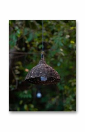 Close-up of a wicker lamp with a blurred garden background