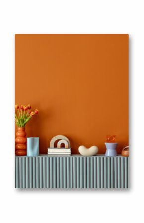 Minimalist orange wall with sideboard decorated with tulips, candles and contemporary decorative objects. Copy space.