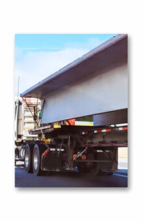 Heavy truck transports large concrete beam on busy highway during bright daylight near an overpass