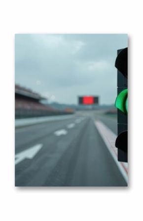 Green traffic light signals start at race track intersection. Vehicles proceed on motor sport event under cloudy sky. Safety governance for race management and competition.