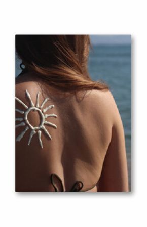 Sun image made with sunscreen on woman's back. Sunbathing on the beach. Close-up. Woman in swimsuit on the beach, back view. Using sunscreen. Concept of beach vacation, seaside resort, beach holiday