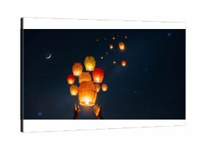 Man hand releasing sky lantern into night star with crescent moon. Celebrating Diwali festival tradition for good luck and wishes.
