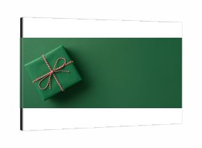 A neatly wrapped green gift with red and white twine sits on a solid green backdrop, conveying holiday gifting, festive charm, and seasonal greetings for Christmas and New Year campaigns