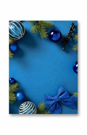 Christmas card. Frame of fir branches with blue balls and festive ornaments on a vibrant blue background