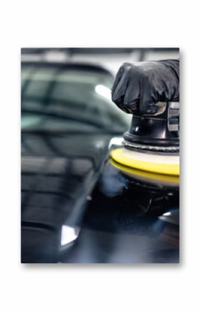 Hands of professional car service worker polishing black luxury car hood in auto repair shop.