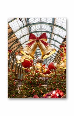 London, UK - December 2, 2024, Christmas-decorated Covent Garden. A view through fir trees of red bells and ornaments.