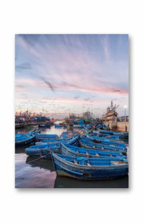 Morocco waterfront at sunset with motion blur of seagulls flying over blue boats