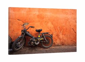 Old moped leans against an orange wall