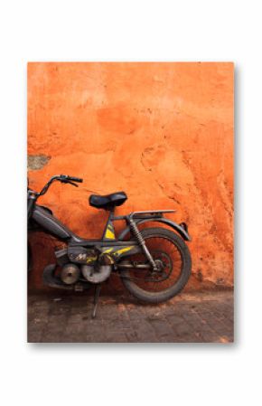 Old moped leans against an orange wall