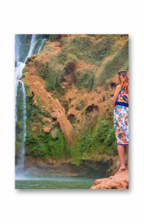 Beautiful waterfall in Morocco. Back of woman in beautiful dress looking fall Ouzoud. Exotic nature of North Africa,