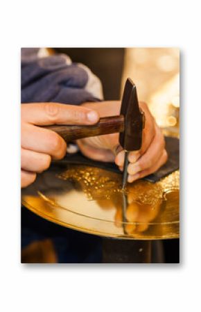 Craftsman hands with hammer working on a golden plate
