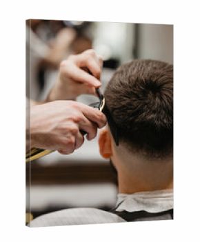 Barber uses clipper on mans hair, near forehead, ear, chin, temple