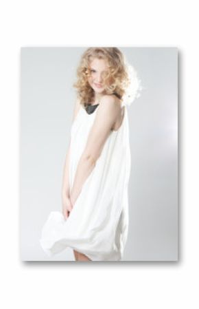 Young blonde girl posing in studio in white dress