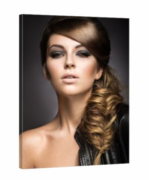Beautiful girl with bright make-up, perfect skin and hairstyle as a braid.Picture taken in the studio on a gray background