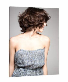 Awesome caucasian attractive joyful happy sexy female model is shaking head with brunette hair in studio wearing nice dress, isolated on gray background