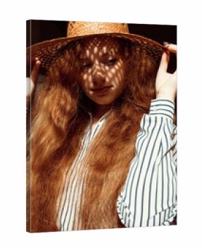 Elegant young red haired model in straw hat with shadow on her face