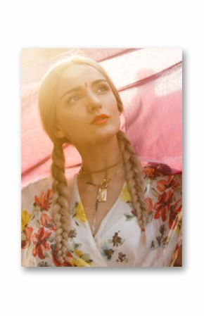 Close-up portrait of a beautiful young woman with a gorgeous bindi on her forehead. Long blonde hair is tangled in hairstyle. She is covered with a beautiful purple silk scarf with small prints.