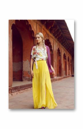 A beautiful young woman walking with a gorgeous bindi on her forehead. Long blonde hair is tangled in wonderful hairstyle. She is palying with a beautiful purple silk scarf with small prints.