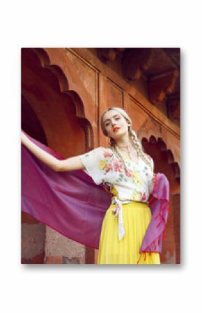 A beautiful young woman walking with a gorgeous bindi on her forehead. Long blonde hair is tangled in hairstyle. She is palying with a beautiful purple silk scarf with small prints.