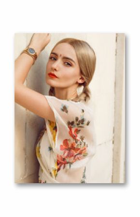 Close-up portrait of a beautiful young woman with gorgeous bindi on her forehead. Long blonde hair is tangled in wonderful hairstyle. And she is dressed in a pretty dress with floral print.