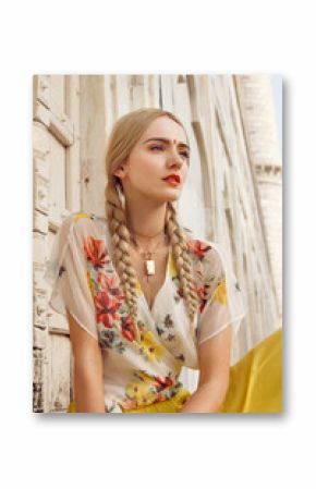 Close-up portrait of a beautiful young woman with a gorgeous bindi on her forehead. Long blonde hair is tangled. She is dressed in a pretty shirt with floral print and yellow skirt