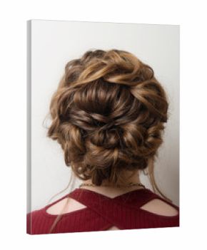 Wedding hairstyle bun on the head of brown-haired women on a gray background close-up rear vie