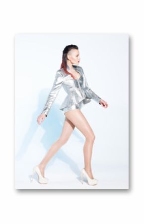Fashion model posing in a silver suit on a white background. Light blue shadow. Stylish young woman in avant-garde clothes and unusual hair