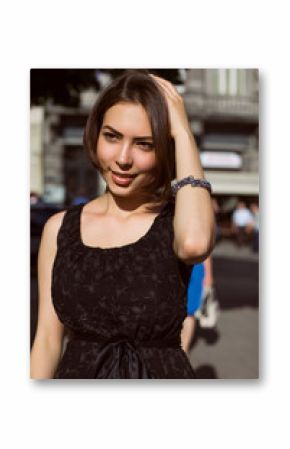 Gorgeous brunette model with bronze tan posing on the street in a fashionable dress