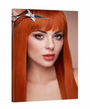 Beautiful young woman with a bright makeup and a smooth long hair holds metal scissors. Model with red hair. Hair salon, haircut. Care and beauty hair products. Perfect make-up