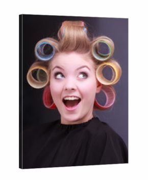 Funny blond girl hair curlers rollers by hairdresser in salon