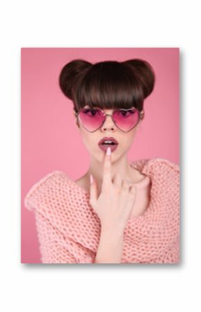 Beauty wow. Fashion surprise teen girl model. Brunette in heart sunglasses with matte lips and hairstyle posing over studio pink background.