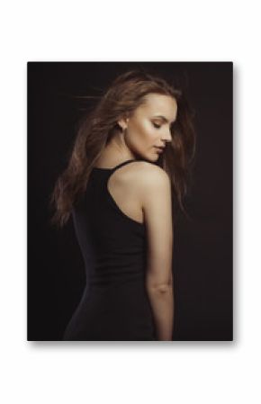 Stylish brunette model in black dress with curly hair in motion