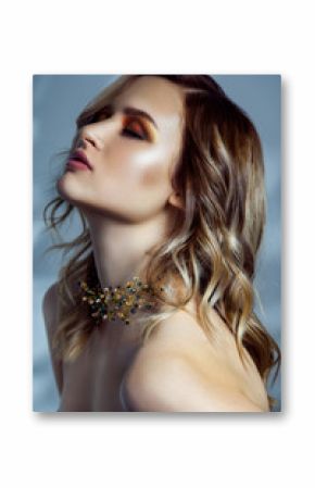Beauty portrait of beautiful fashion model with makeup, colored wavy hairstyle and accessories on her neck. studio shot on blue background. 