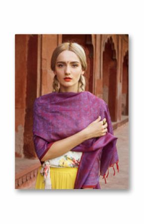 Close-up portrait of a beautiful young woman with gorgeous bindi on her forehead. Long blonde hair is tangled in hairstyle. She is covered with a beautiful purple silk scarf with small prints.