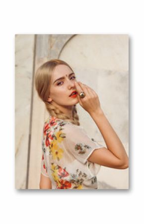 Close-up portrait of a beautiful young woman with gorgeous bindi on her forehead. Long blonde hair is tangled in wonderful hairstyle. And she is dressed in a pretty dress.