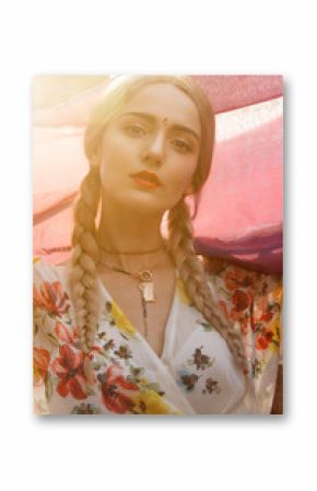 Close-up portrait of a beautiful young woman with a gorgeous bindi on her forehead. Long blonde hair is tangled in hairstyle. She is covered with a beautiful purple silk scarf with small prints.