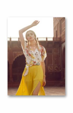 A beautiful young woman walking with a gorgeous bindi on her forehead. Long blonde hair is tangled in wonderful hairstyle. And she is dressed in a pretty shirt with floral print and yellow skirt.