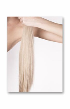 Healthy platinum blonde hair in a tale. Girl holding her hair in a hand.