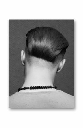 Close up portrait of handsome fashionable charismatic man's back posing over dark gray background. Modern stylish haircut. Monochrome studio shot
