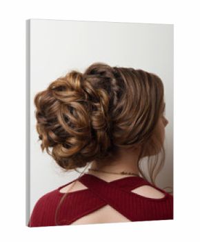 Wedding hairstyle bun on the head of brown-haired women on a gray background close-up rear vie