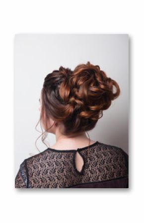 Wedding hairstyle bun on the head of brown-haired women on a gray background close-up rear vie