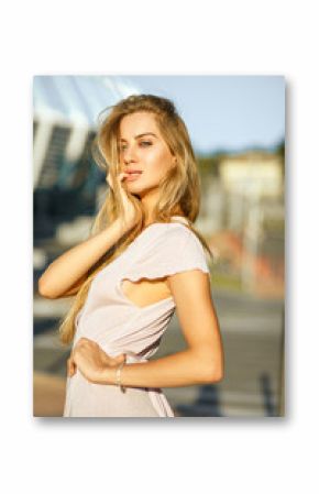 Luxurious blonde girl with long hair posing at the background of street in sun light