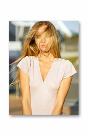 Wonderful blonde woman with long hair posing at the background of street in sun light