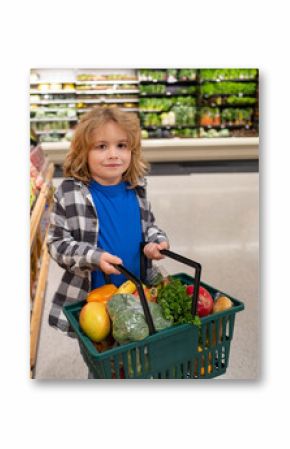 Child with shopping basket full of vegetables and fruits. Kid in a food store. Supermarket shopping and grocery shop concept. Child with shopping basket.