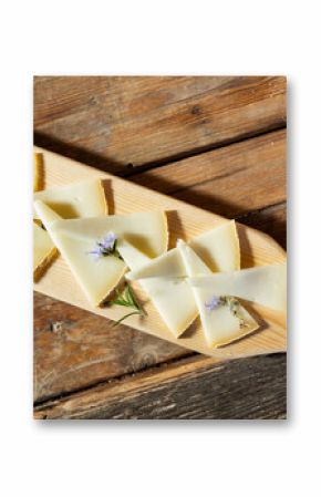 From above of delicious cheese slices served with rosemary sprouts and flowers on wooden cutting board in restaurant