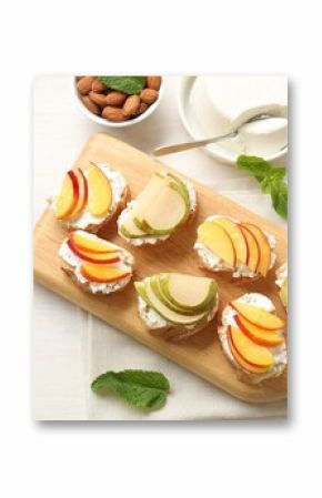 Delicious ricotta bruschettas with pears and apricots among products on white wooden table, flat lay