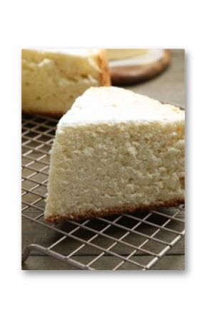 Delicious cut sponge cake with powdered sugar on wooden table, closeup