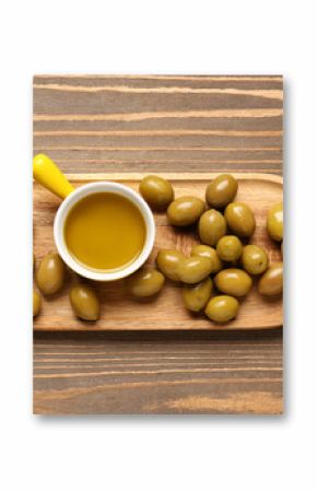 Ripe olives and bowl with oil on wooden background